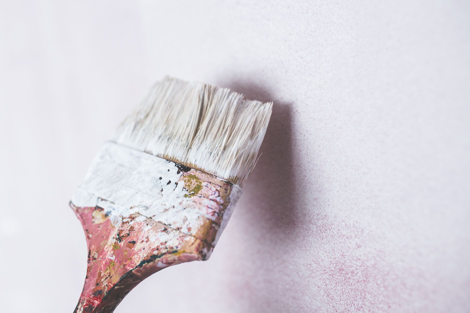 Close-up of a paintbrush applying white paint on a wall, showcasing a minimalist aesthetic in Santa Monica, CA