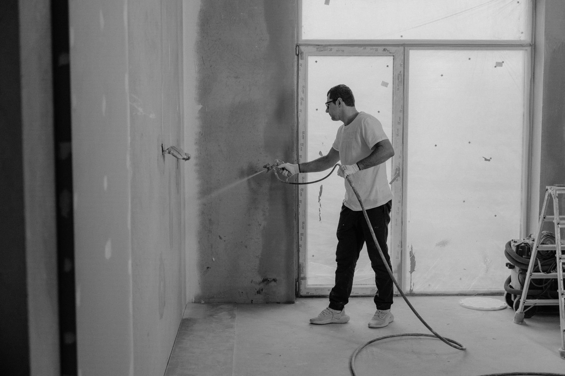 A worker paints an interior wall with a spray gun during a renovation project in Santa Monica, CA